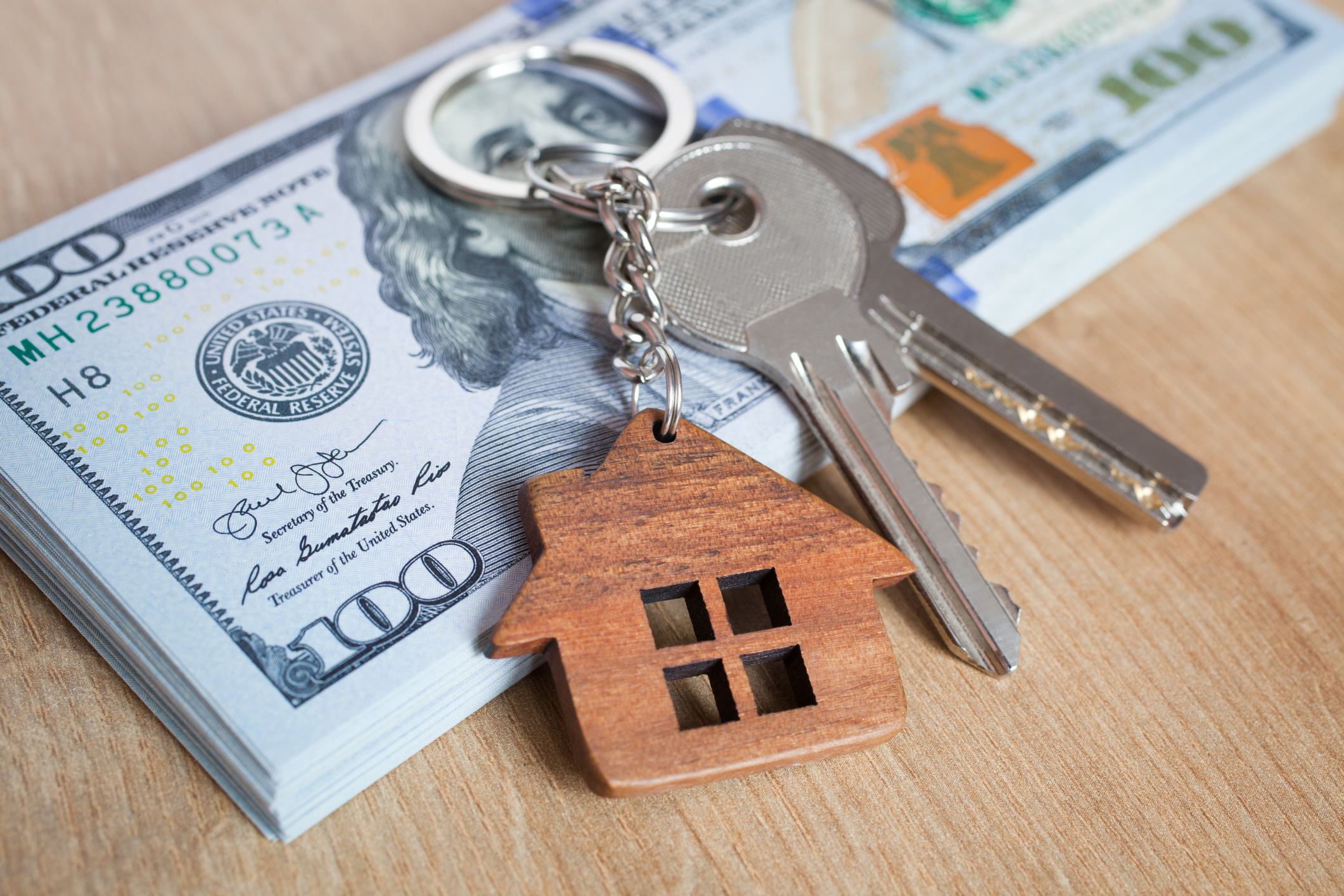 image of keys with a house keychain on a 100 dollar bill