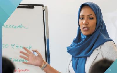 woman in hijab teaching in front of a whiteboard