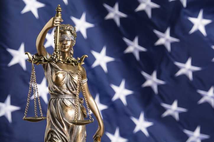 Scales of justice in front of an American flag