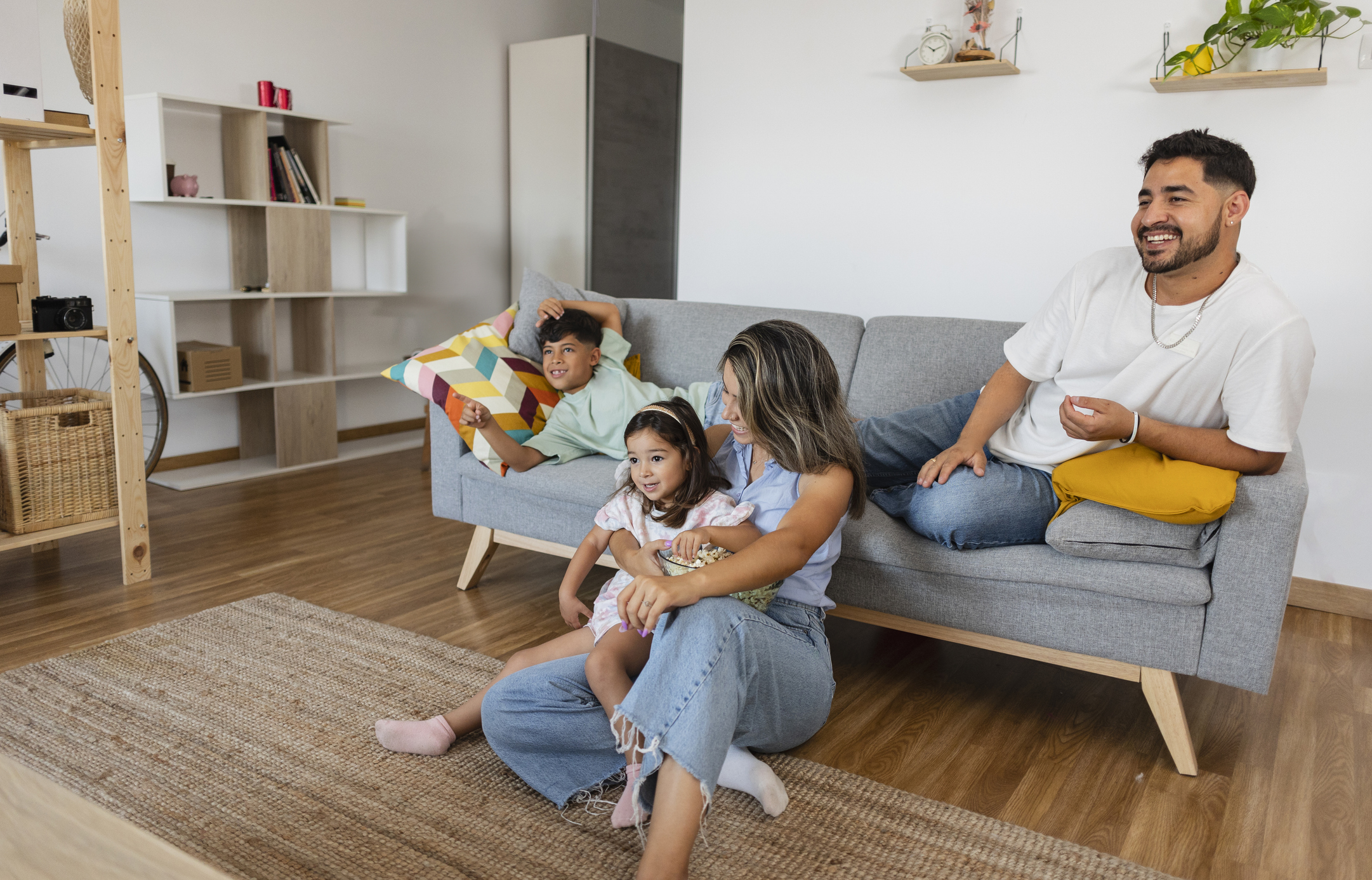 Relaxed family watching a movie on the couch, sharing snacks and enjoying quality time at home.