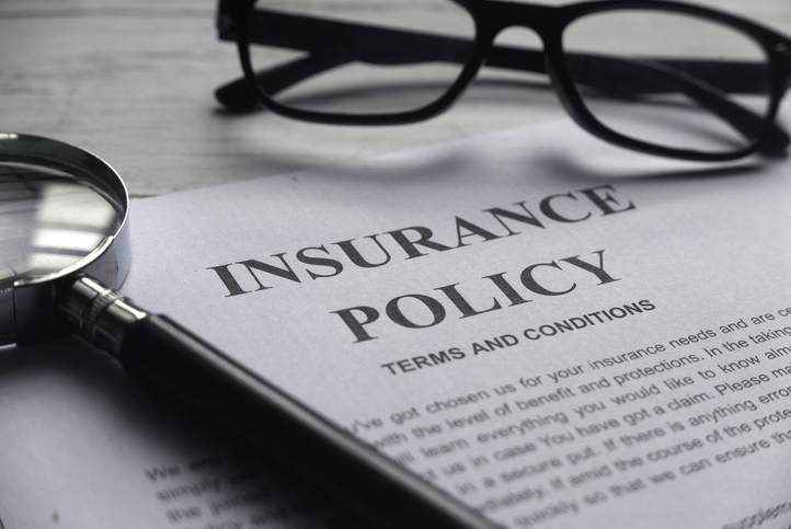 Photo of an insurance policy alongside a magnifying glass and a pair of reading glasses.