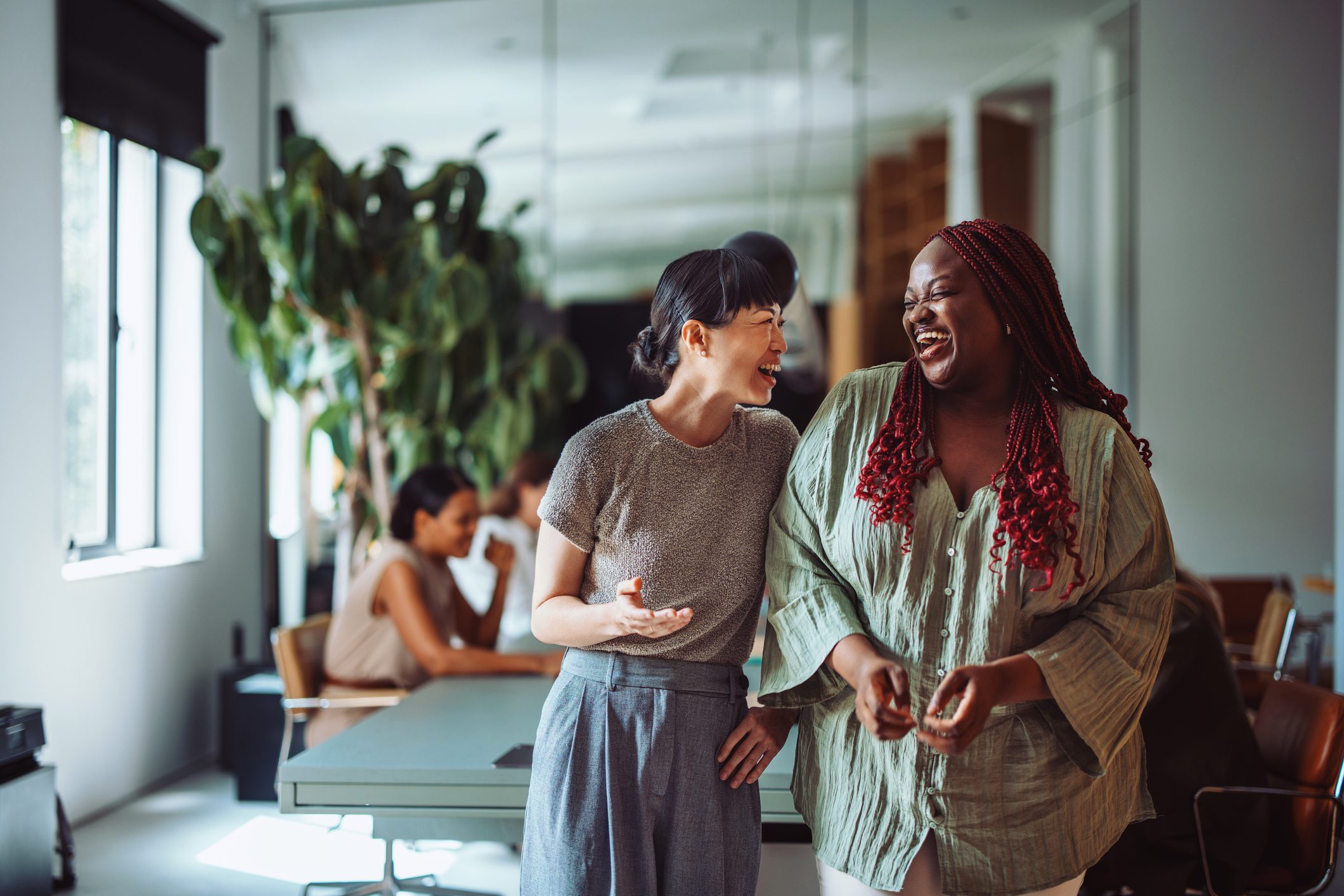 two women laughing in a workplace
