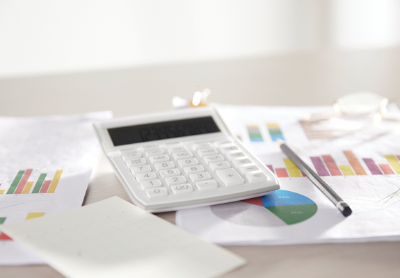 calculator sitting on a pile of files with graphs on them