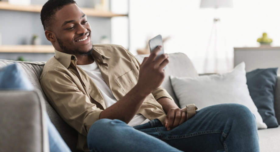 man sitting on couch looking at phone and smiling