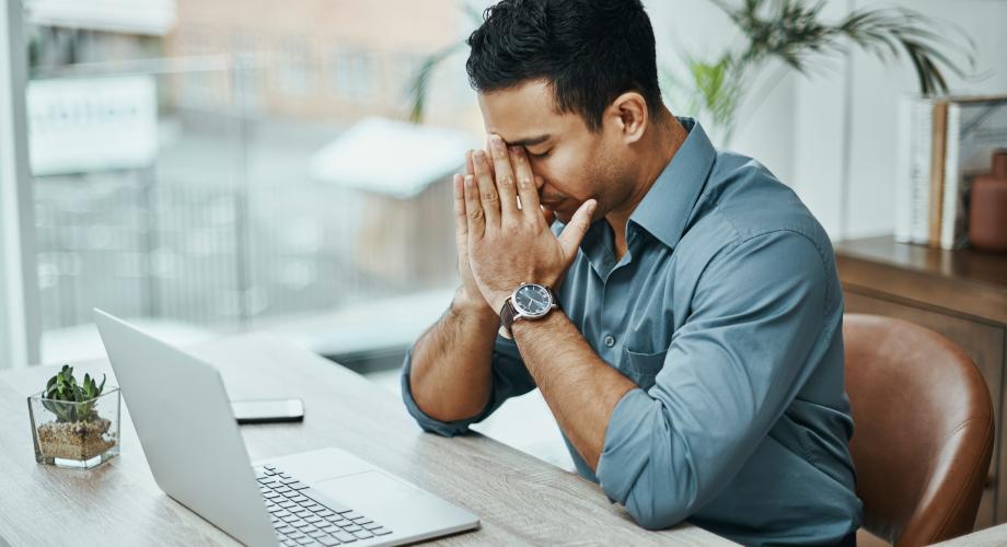 businessman looking stressed while working at laptop