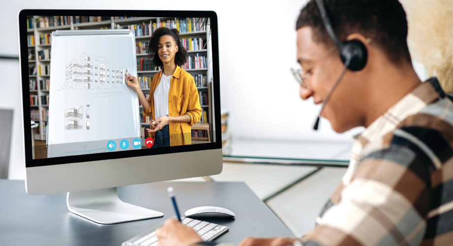 man in headset watching a woman presenting something in a video on his computer