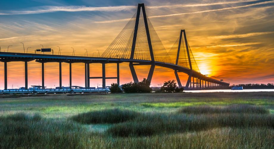 Photo of a vehicular bridge crossing a river at sunset.