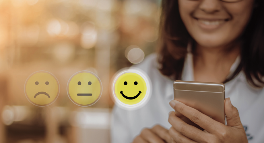 woman looking at phone with review-style smiley faces overlaid