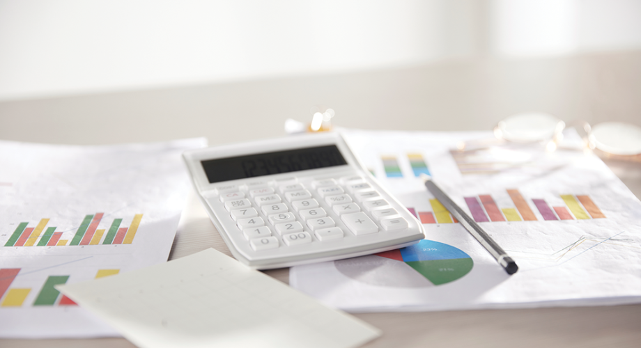 calculator sitting on a pile of files with graphs on them