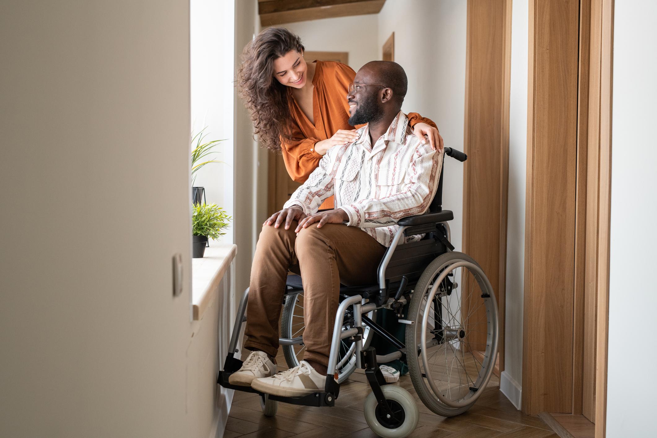 man in wheelchair in hallway with woman
