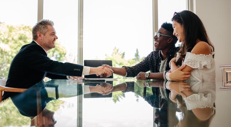 two people shaking hands with a man in professional attire