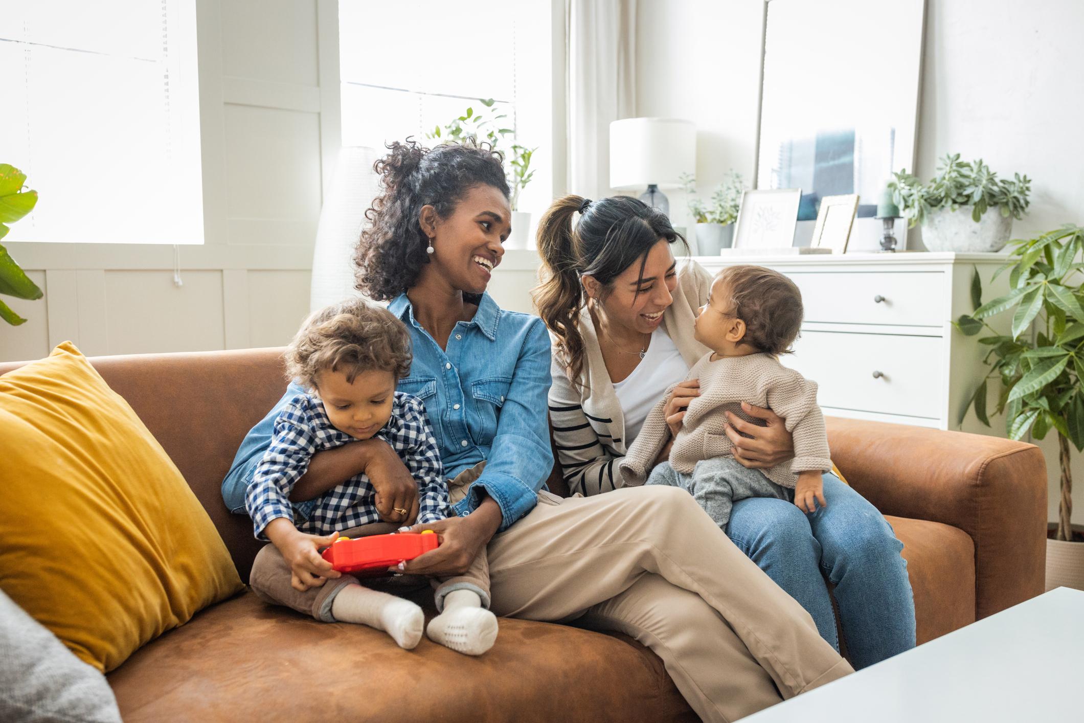 two women with young children sitting on a couch