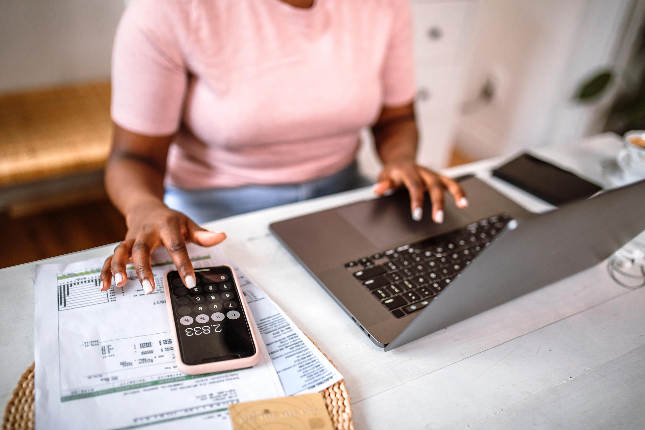 woman using calculator and working on computer