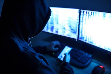 hooded figure hacking a computer